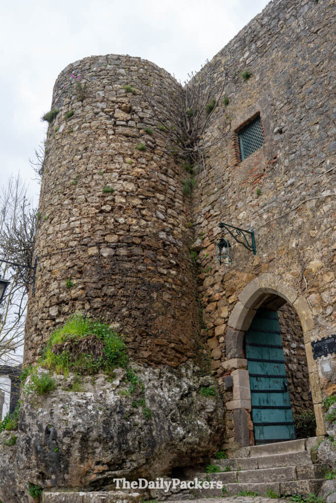 The stone tower and arched green doorway entrance to the historic Obidos Castle.