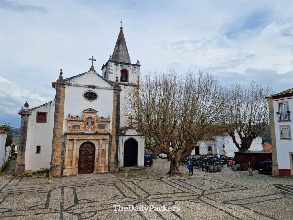 The grand exterior of Saint Mary Church facing the open cobblestone square in Óbidos.