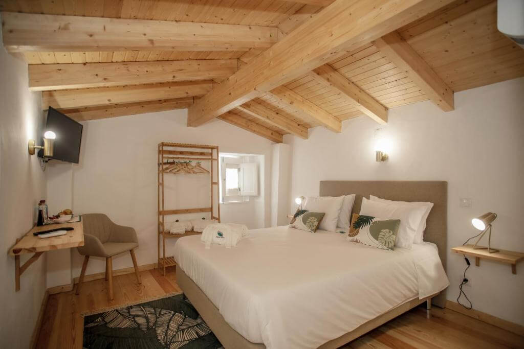 Cozy bedroom at Patio House with a large bed under rustic exposed wooden ceiling beams.