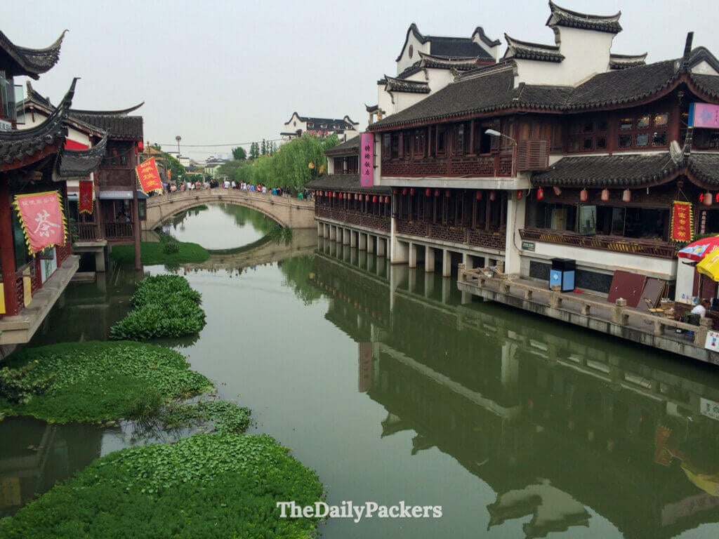 Pont en arc de pierre sur un canal vert bordé de bâtiments en bois de la dynastie Ming dans la vieille ville de Qibao, Shanghai