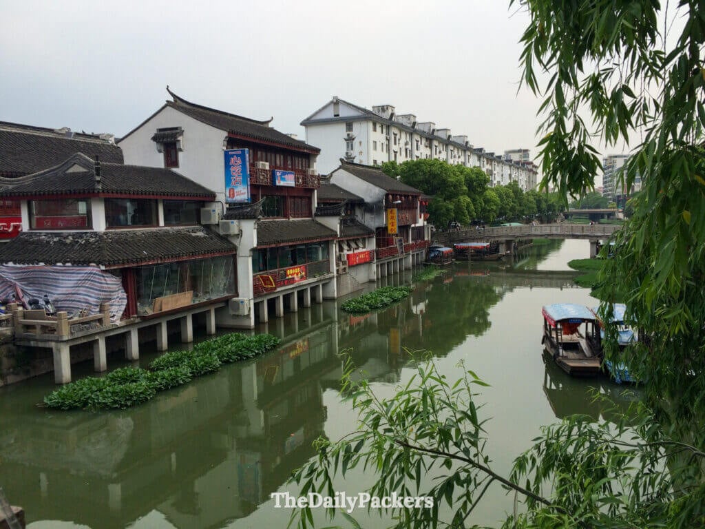 Maisons traditionnelles au bord du canal et bateau touristique en bois reflétés dans la voie navigable de la vieille ville de Qibao, Shanghai