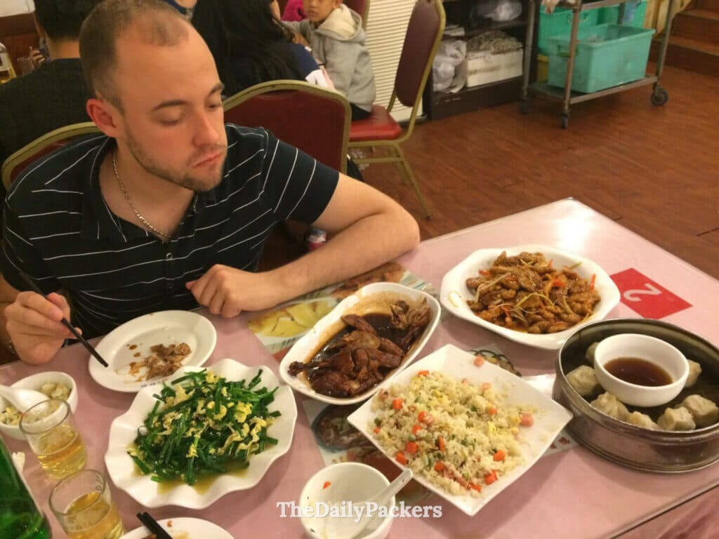 Voyageur mangeant un assortiment de plats traditionnels de Shanghai, notamment des raviolis et des sautés, dans un restaurant local