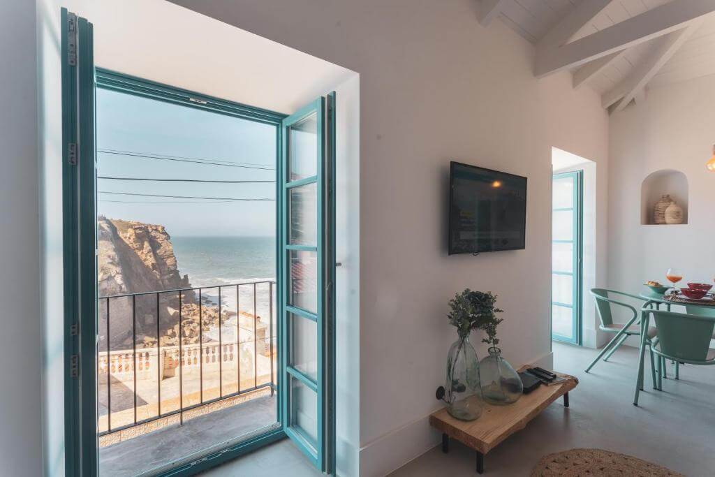 Open balcony window overlooking a rocky coastal cliff and the ocean in Portugal.