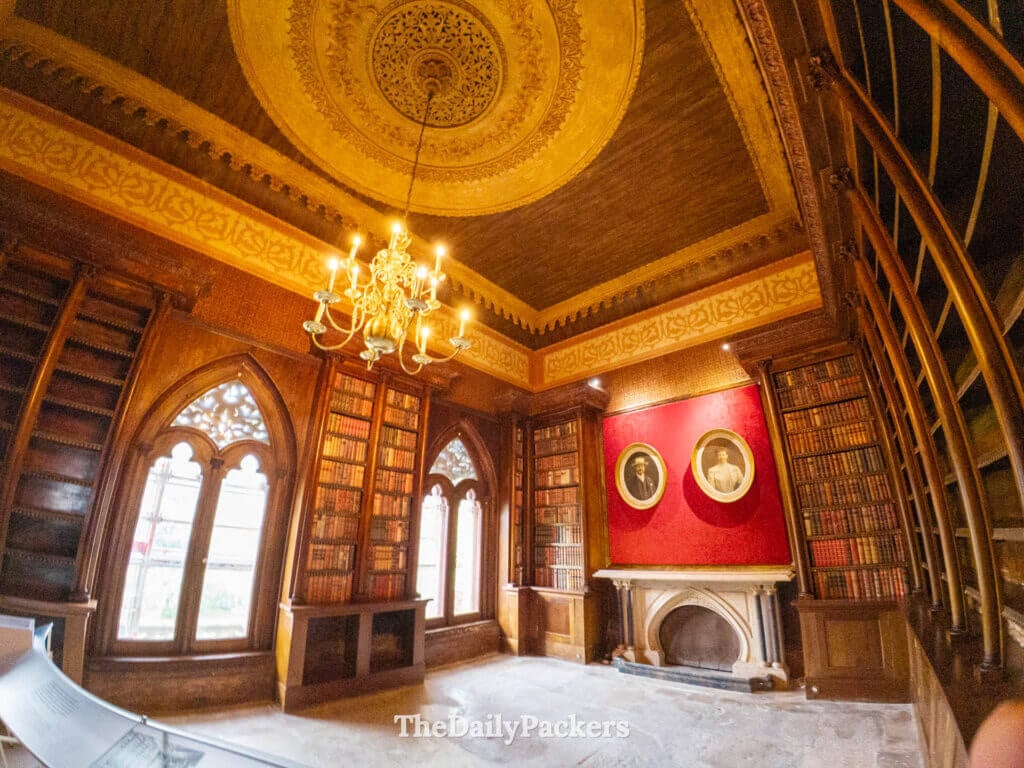 La bibliothèque historique du palais de Monserrate avec des étagères en bois sombre et une porte sculptée.