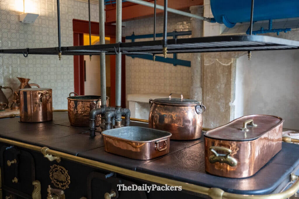 Une cuisine de palais aux murs de pierre présentant d’anciens fours et du matériel culinaire d’époque.