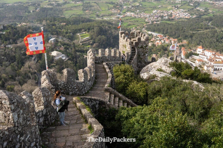 A mother holds her baby on the medieval stone walls overlooking the scenic Sintra valley.