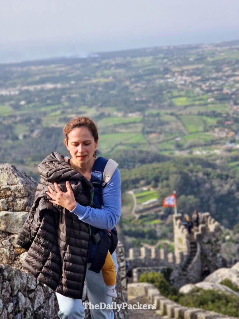 Close-up of a mother holding her jacket while walking along the high-altitude Sintra castle ruins.