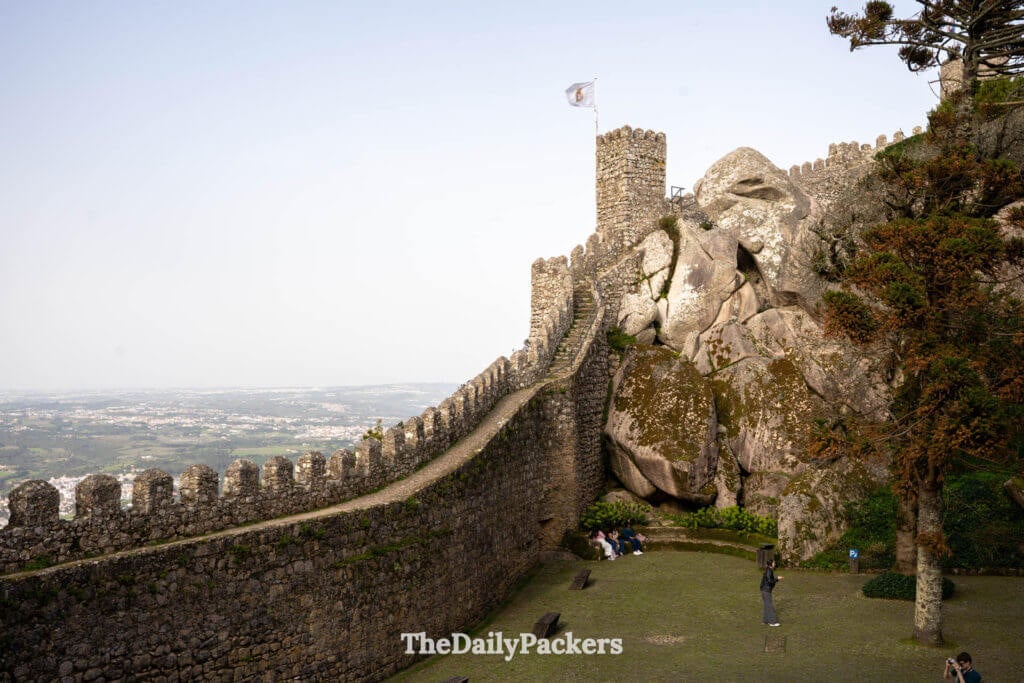 A grassy inner courtyard flanked by massive boulders and fortified walls at the Moorish Castle.