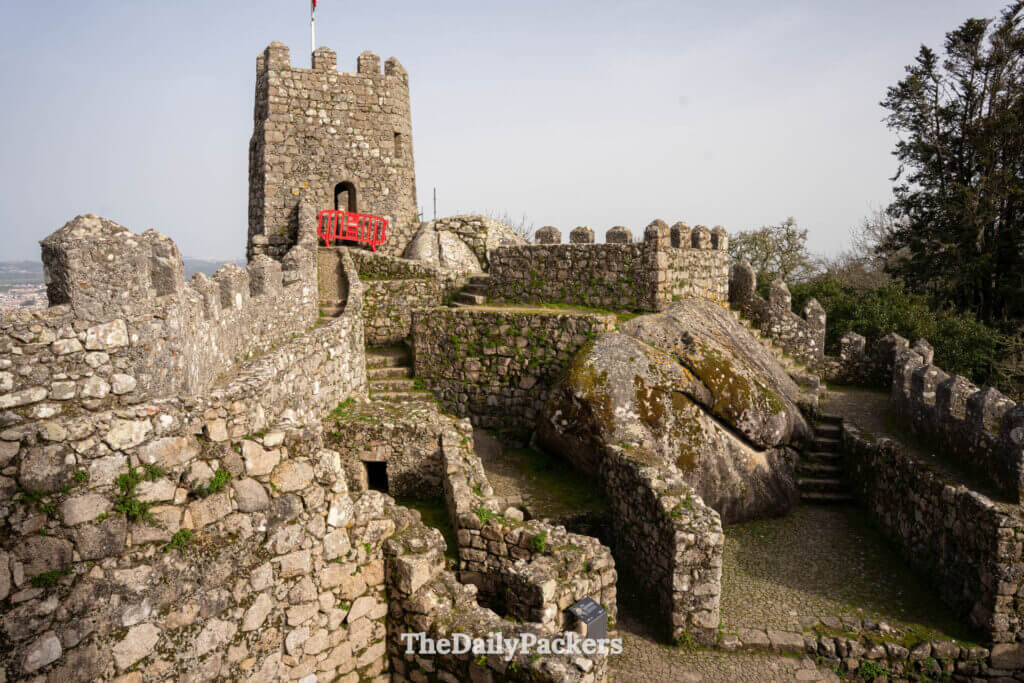 Historic stone ruins and a fortified tower built around large boulders at Sintra Moorish Castle.