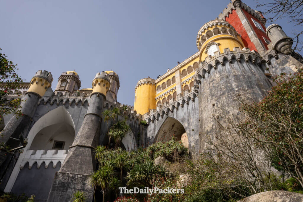 Looking up at the massive stone arches and vibrant ramparts of Pena Palace in Sintra, Portugal.