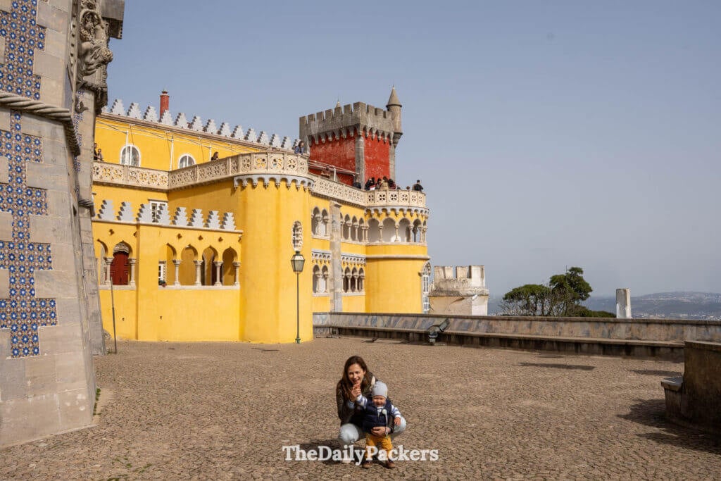 A mother and baby posing in the open yellow inner courtyard of Pena Palace.