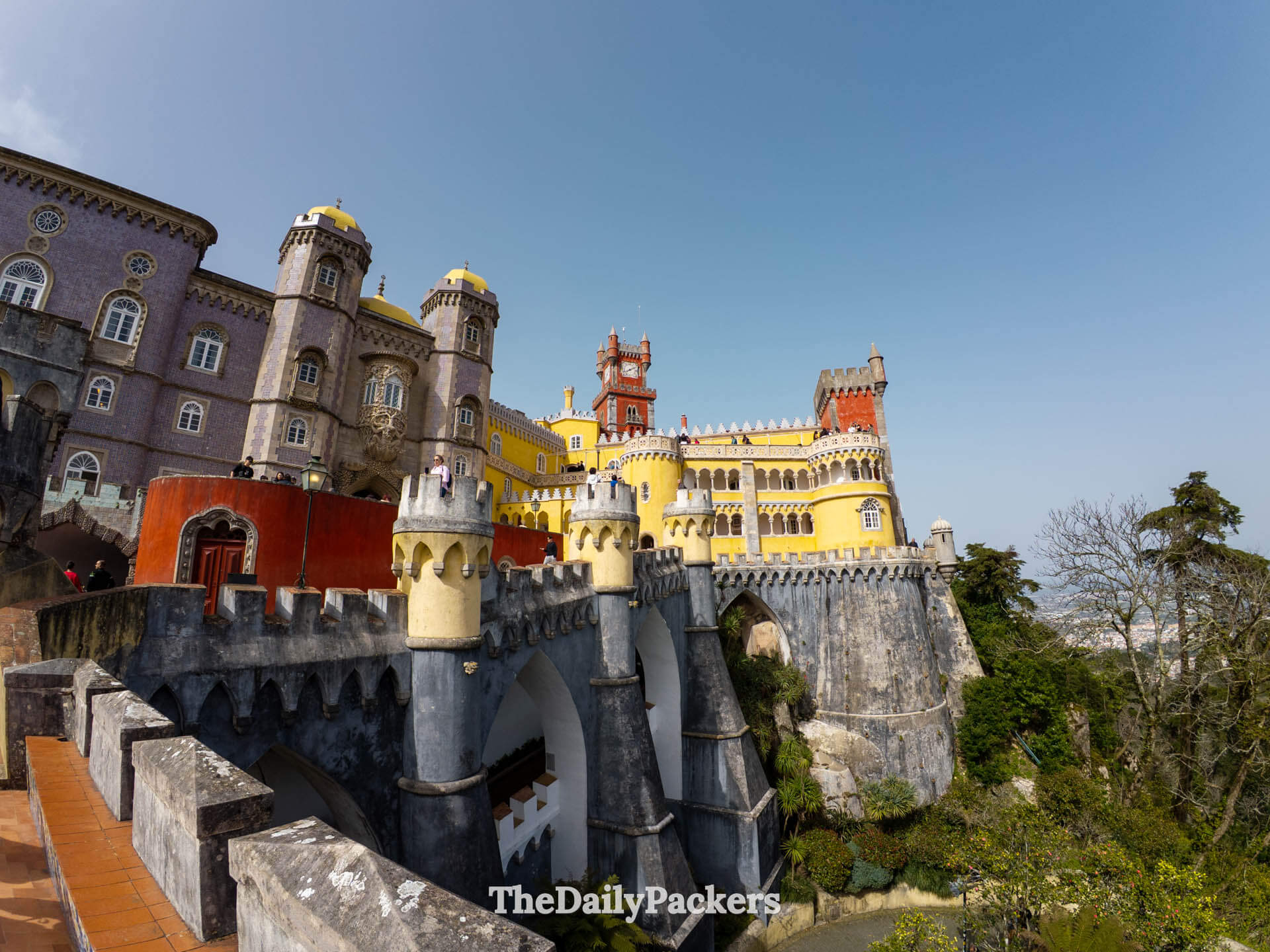 Wide-angle shot of the dramatic stone battlements and colorful facades of Pena Palace.