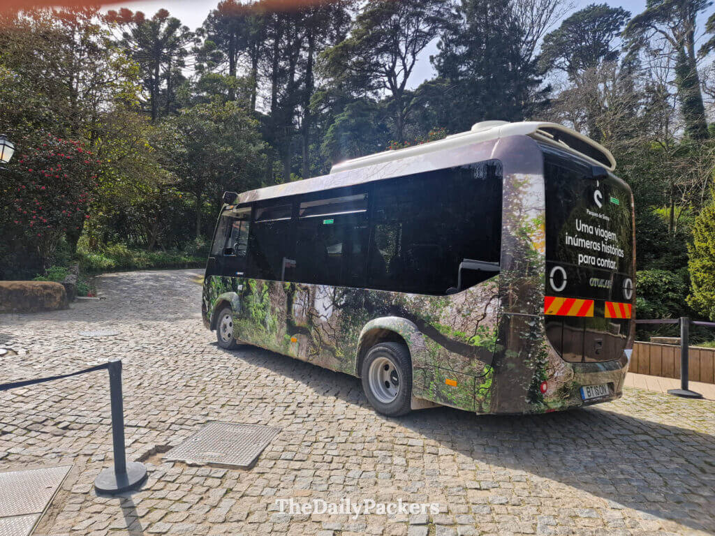 The Parques de Sintra transfer shuttle bus parked on a cobblestone road among the trees.