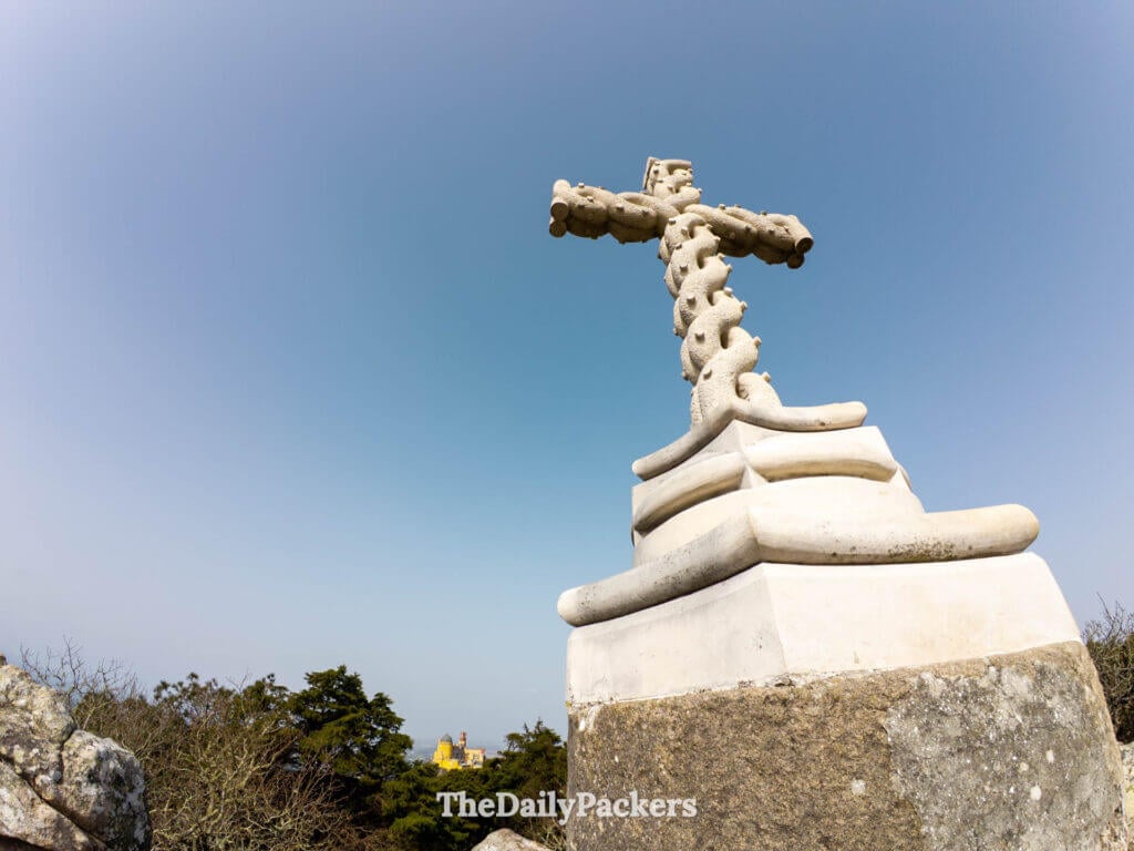 Low-angle view of the stone High Cross (Cruz Alta) monument against a clear blue sky.