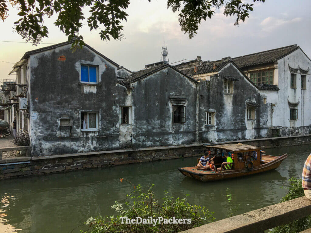 Gondole traditionnelle en bois passant devant d’anciens bâtiments blanchis à la chaux sur le canal de Suzhou
