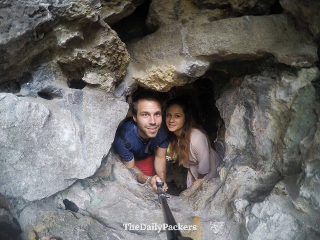 Couple explorant un passage étroit et rocheux dans le labyrinthe de pierres du Jardin du Bosquet du Lion à Suzhou