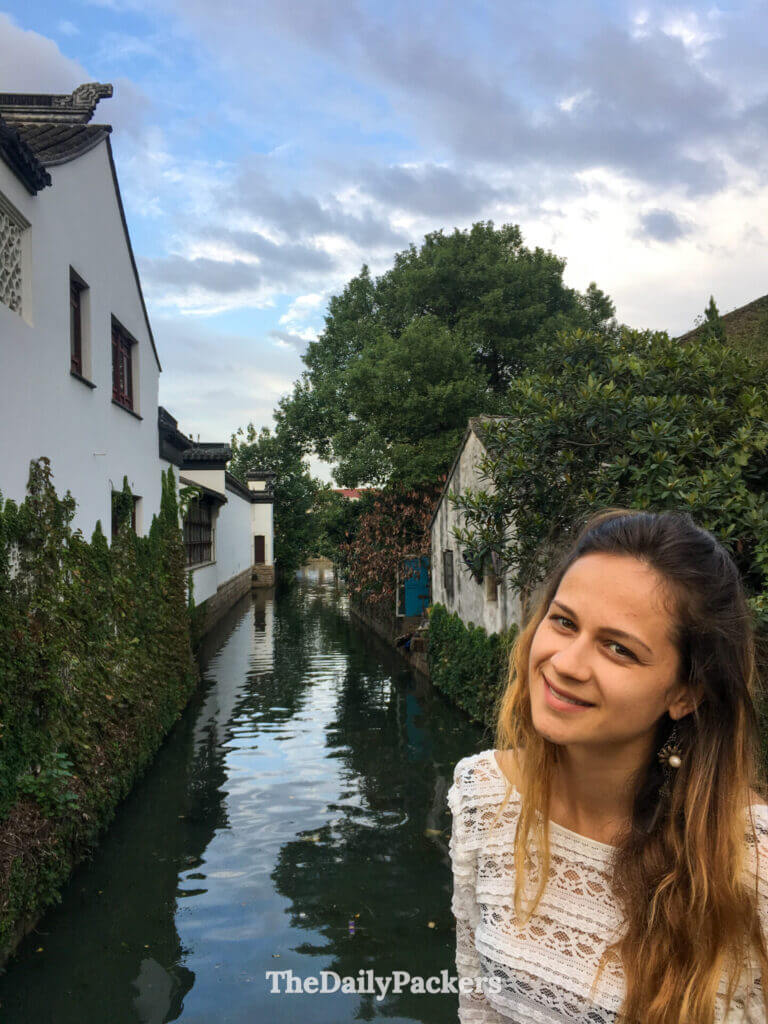 Voyageur souriant à côté d’un canal étroit et paisible bordé de maisons blanchies à la chaux dans la ville d’eau de Zhouzhuang