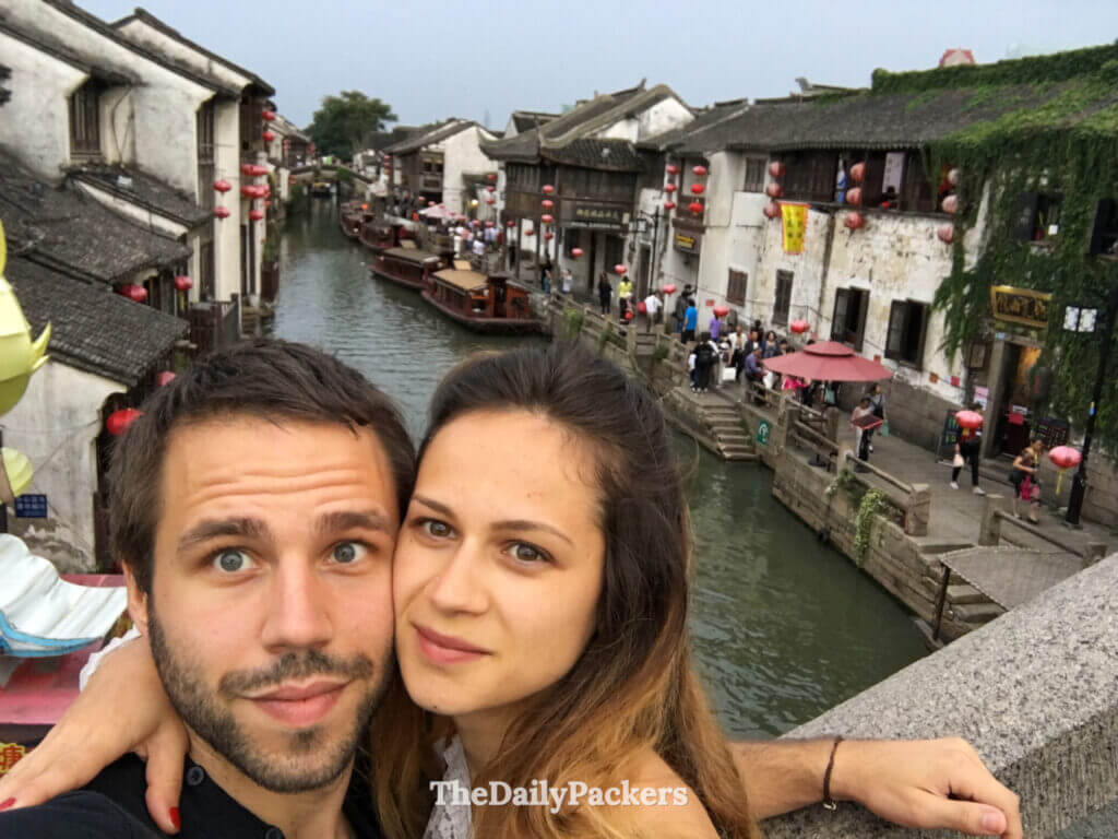 Selfie de couple sur un pont au-dessus du canal animé de la ville d’eau de Tongli, bordé de lanternes rouges