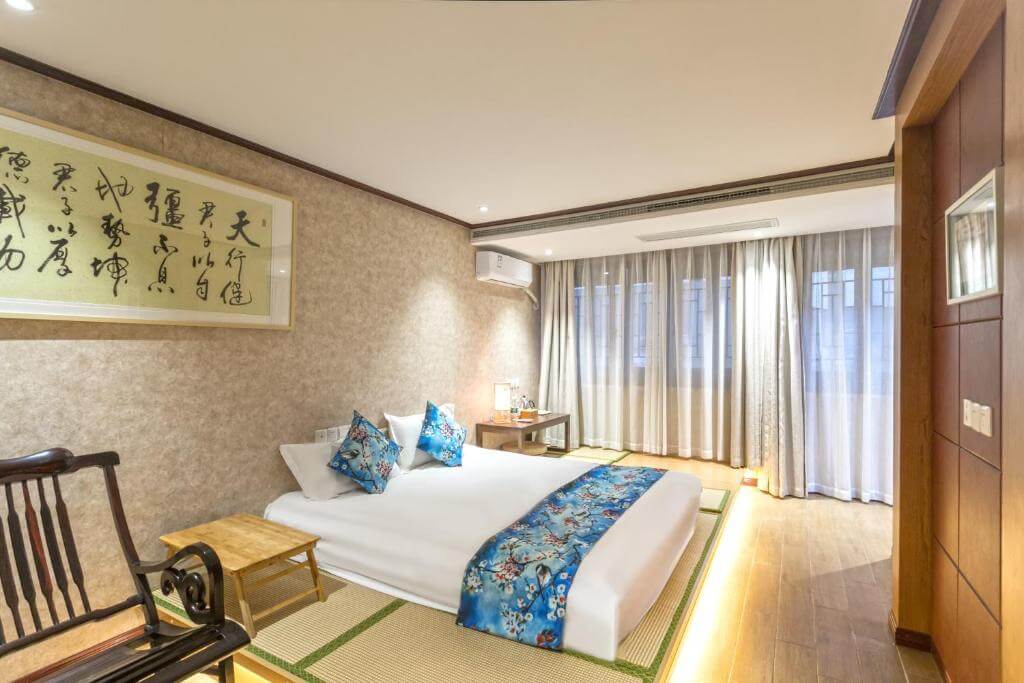 Elegant Chinese-style room with calligraphy art and floral bedding at Suzhou's Jade Snow Lodge
