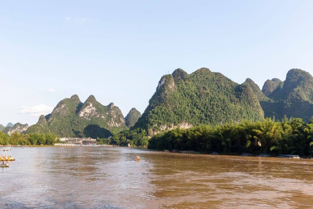 A serene landscape of karst mountains and the Li River in Guilin, China, under a clear sky.